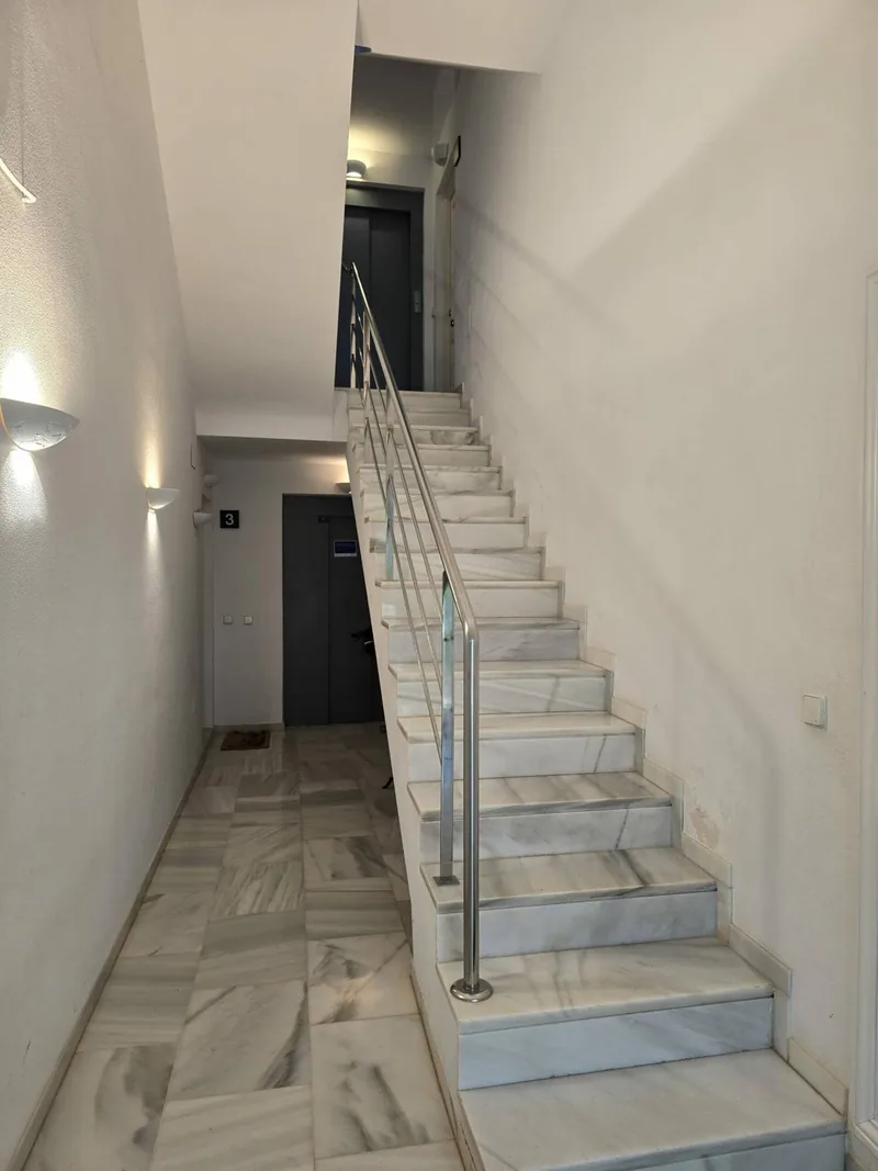 Escalera de comunidad con barandilla de cristal limpia, en Palma